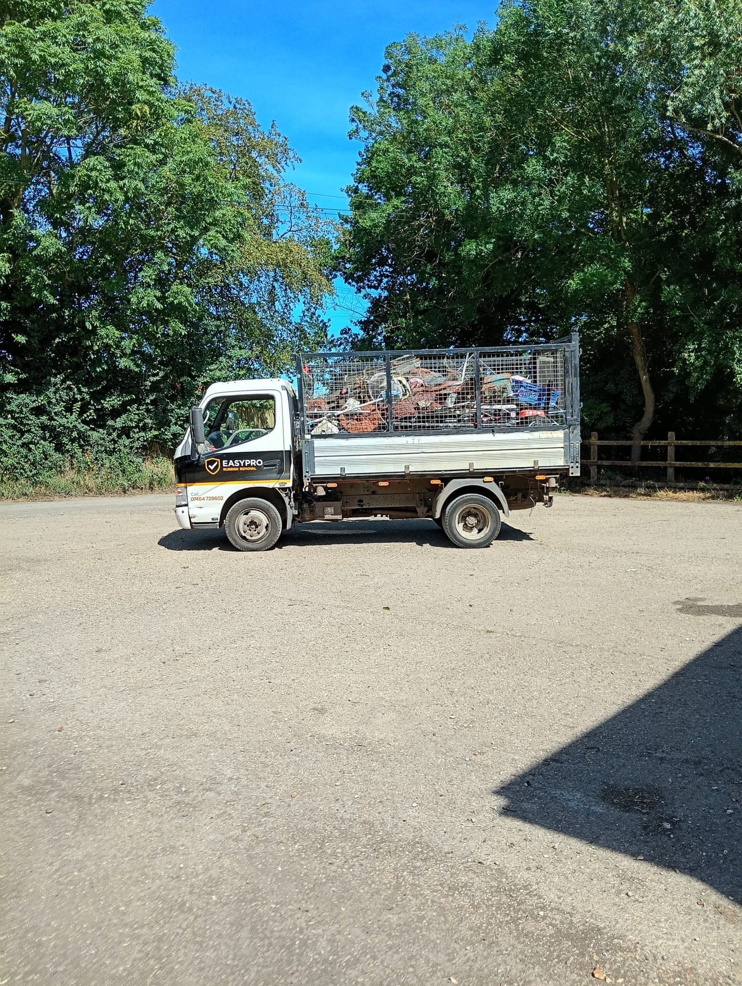 The EasyPro tipper seen side-on, branding visible on the cab door, bed loaded with timber and scrap