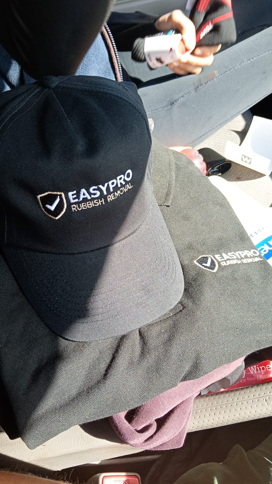An EasyPro branded cap resting on folded branded workwear