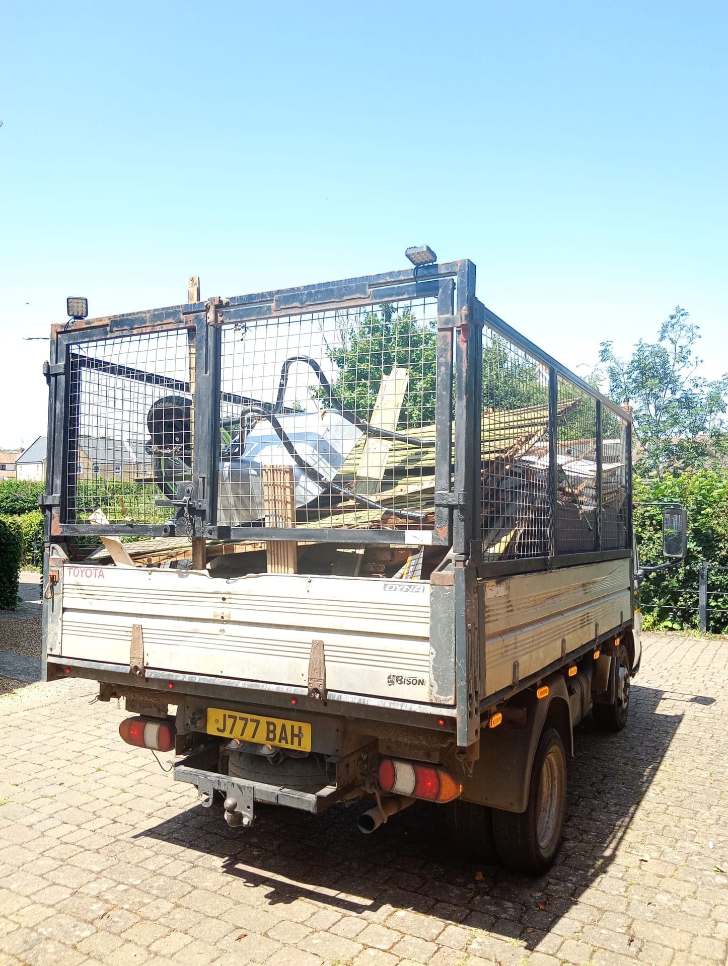 The rear of the caged tipper loaded with scrap metal and broken garden furniture